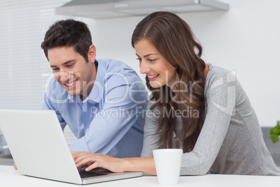 Happy couple using a laptop in the kitchen