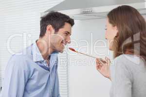 Woman feeding husband while cooking