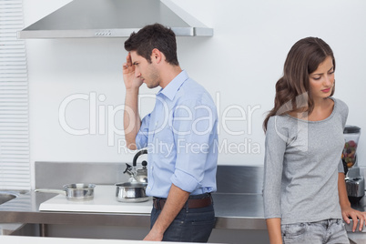 Couple sulking at each other in the kitchen