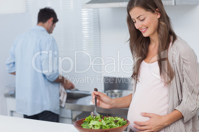 Pregnant woman mixing a salad in the kitchen