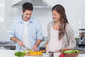 Man chopping mushrooms next to his pregnant partner