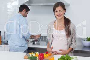 Pregnant woman holding her belly in the kitchen