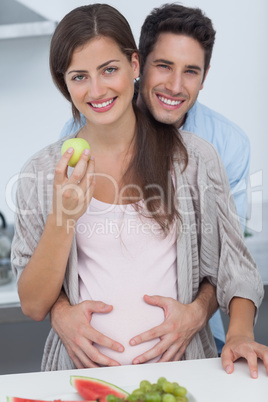 Cheerful man holding the belly of his pregnant wife
