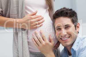 Man listening to the belly of his pregnant wife