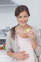 Pregnant woman holding a green apple