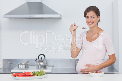 Pregnant woman eating cereal in the kitchen
