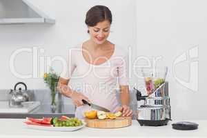 Pregnant woman cutting fruits in the kitchen