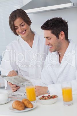 Happy man reading a newspaper while having breakfast