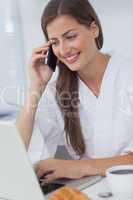 Woman phoning and using her laptop