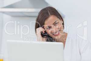 Cheerful woman on the phone using her laptop