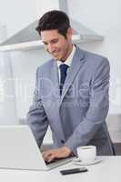 Businessman using his laptop while having breakfast