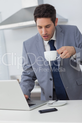 Businessman using his laptop while drinking coffee