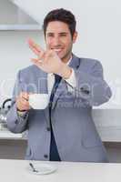 Happy businessman waving at someone in the kitchen