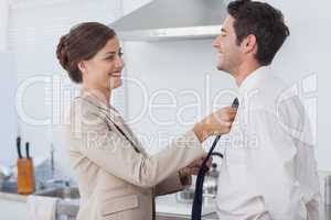 Woman helping her husband to tie his tie