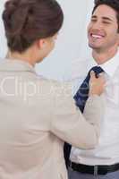 Woman helping her smiling husband to tie his tie