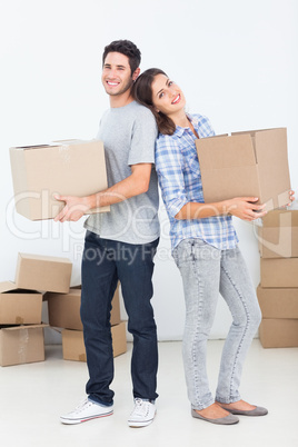 Husband and wife carrying boxes in their new house