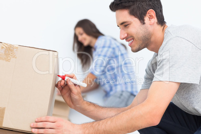 Man writing with a red marker on a moving box