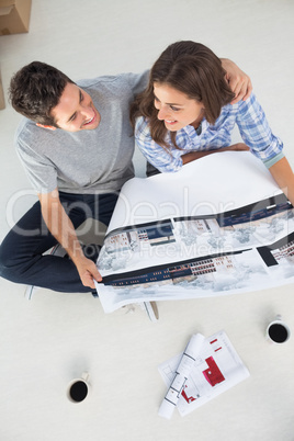 Overview of a husband and his wife holding house plan