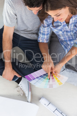 Woman pointing at color charts sitting in her new house