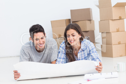 Couple lying on the floor and looking at house plans