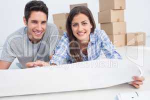 Portrait of a couple lying on the floor and holding a house plan