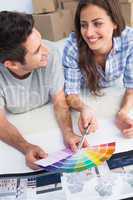 Happy couple looking at a color chart to decorate their house