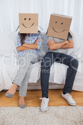 Couple sitting with cardboard boxes on head