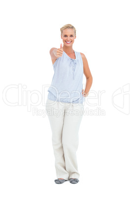 Blonde woman standing with thumbs up smiling at camera