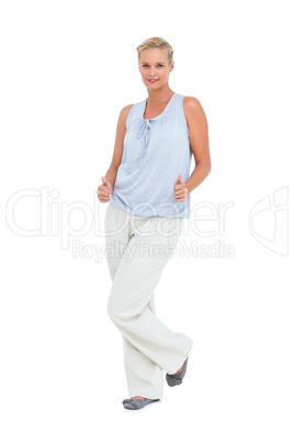Blonde woman standing with thumbs up at her hips