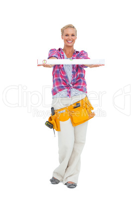 Woman holding a spirit level smiling at camera