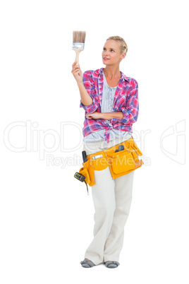Blonde standing while looking at paint brush