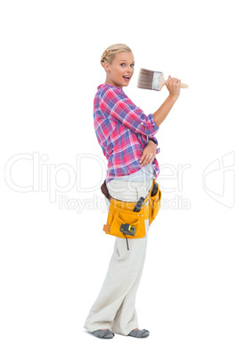 Blonde holding paint brush wearing a tool belt