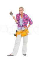 Smiling woman holding paint brush wearing a tool belt