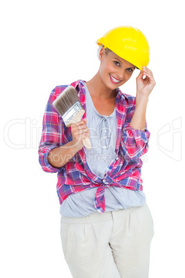 Handy woman touching her helmet and holding paintbrush
