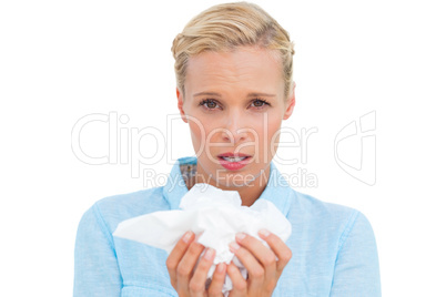Blonde woman sneezing holding lots of tissues