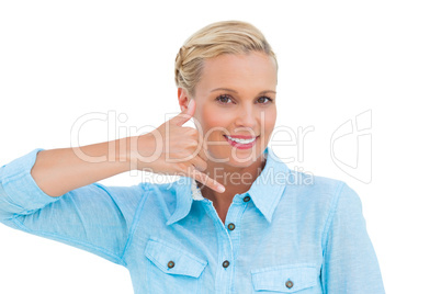 Smiling blonde looking at camera and doing a symbol of phone wit