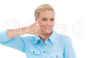 Smiling blonde looking at camera and doing a symbol of phone wit