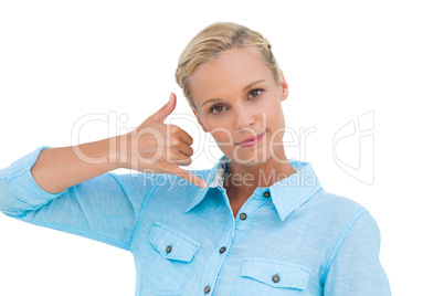 Blonde doing a symbol of phone with her hand and looking at came