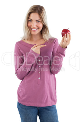 Smiling blonde woman pointing to an apple