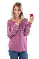 Smiling blonde woman pointing to an apple