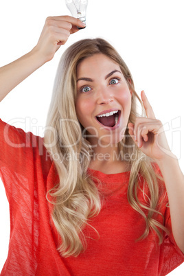 Surprised woman holding light bulb above her head