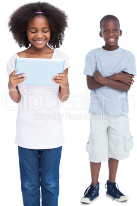 Girl using tablet pc with her brother behind her