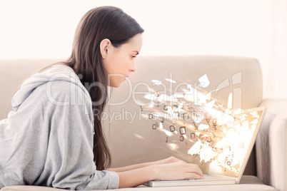 Woman using laptop with binary codes exploding over