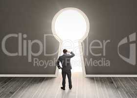 Businessman looking through a keyhole shape door