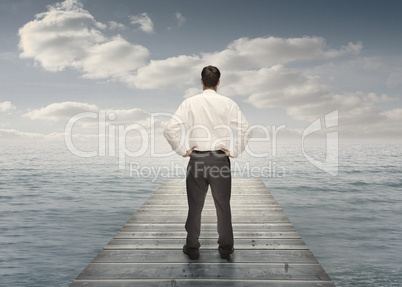 Businessman standing on a bridge with hands on hips