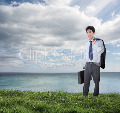 Elegant businessman holding briefcase and his jacket over his sh