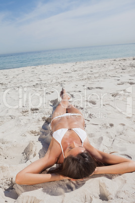 Woman sunbathing on beach in front of ocean