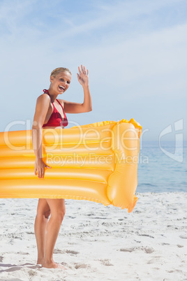 Smiling woman waving and holding lilo