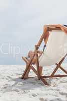 Woman resting on her deck chair in front of ocean