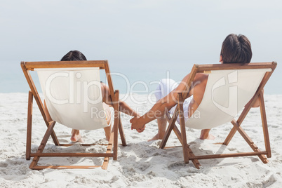 Couple lying on deck chairs